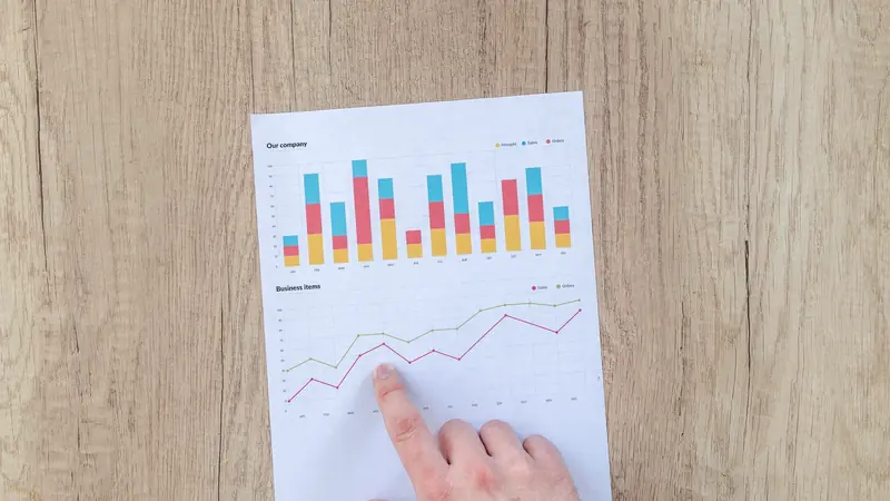 Main pointant un rapport imprimé avec des graphiques sur une table en bois