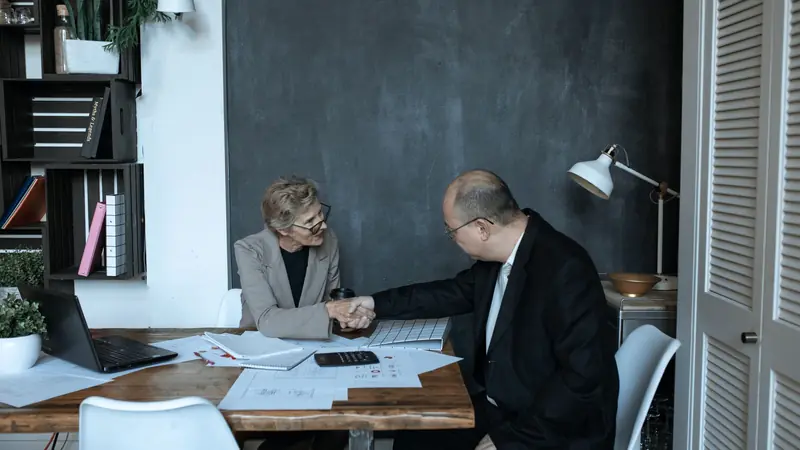 Poignée de main entre deux personnes autour d'un bureau après un entretien