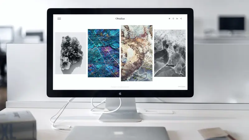 Écran d'ordinateur affichant un site internet avec une galerie d'images sur un bureau blanc